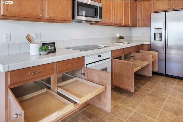 kitchen with light countertops, appliances with stainless steel finishes, and brown cabinets