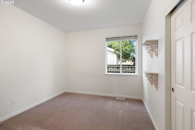 spare room with baseboards, visible vents, and carpet flooring