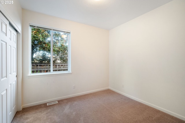 empty room featuring carpet floors, visible vents, and baseboards