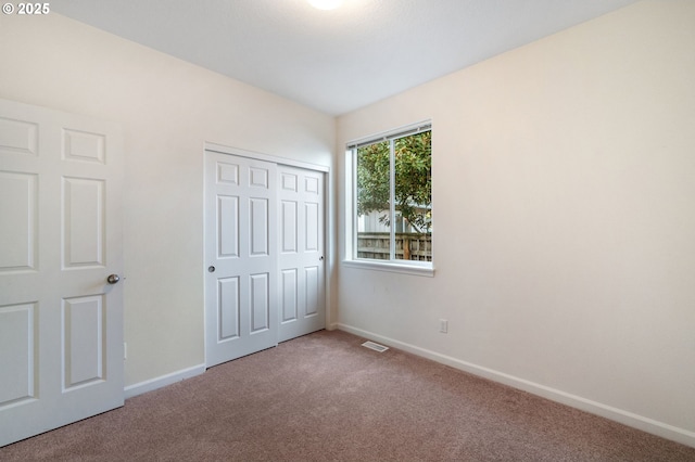 unfurnished bedroom featuring a closet, baseboards, visible vents, and carpet flooring