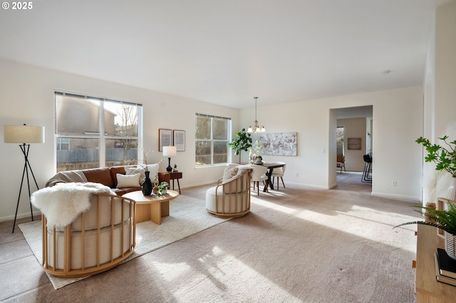 living area featuring baseboards, a notable chandelier, and light colored carpet