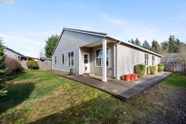 back of property with entry steps, fence, a lawn, and a patio