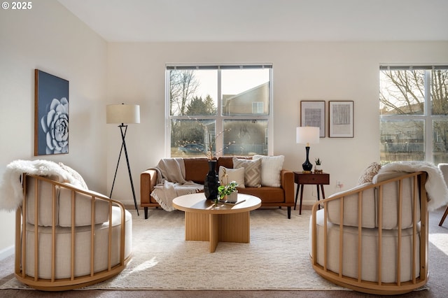 sitting room featuring light carpet, baseboards, and a healthy amount of sunlight