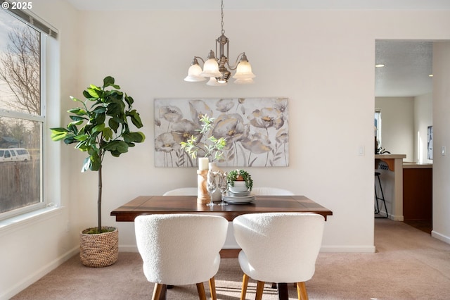 carpeted dining room with breakfast area, baseboards, and a chandelier