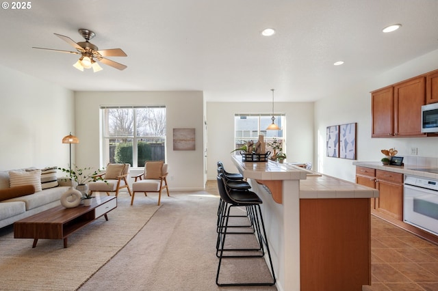 kitchen with tile countertops, white oven, stainless steel microwave, and recessed lighting