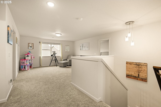 hall with carpet floors, baseboards, and an upstairs landing