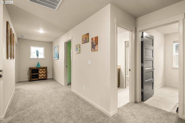 hallway featuring carpet flooring, visible vents, and baseboards