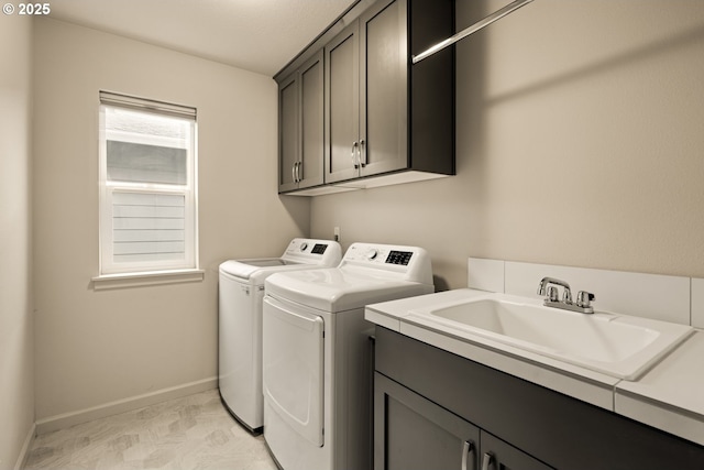 laundry area featuring cabinet space, baseboards, separate washer and dryer, and a sink