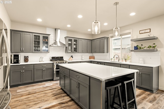 kitchen with wall chimney range hood, gray cabinets, and appliances with stainless steel finishes