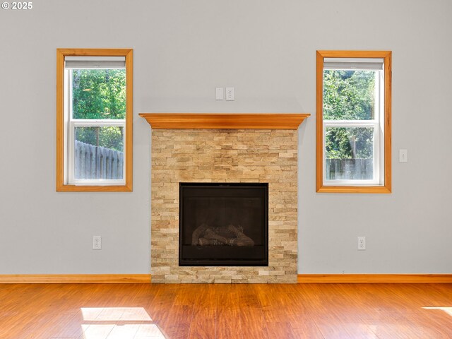unfurnished living room featuring wood finished floors, baseboards, and plenty of natural light