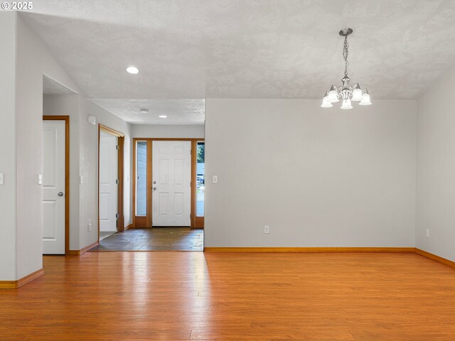 foyer entrance with wood finished floors, a chandelier, baseboards, and recessed lighting