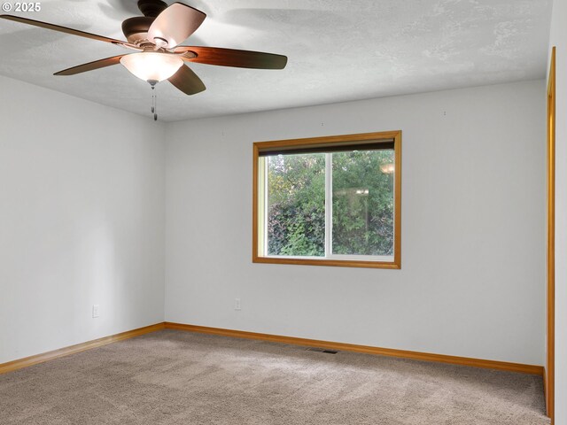carpeted spare room with baseboards, a ceiling fan, and a textured ceiling