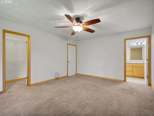 unfurnished bedroom with light colored carpet, baseboards, a ceiling fan, and connected bathroom