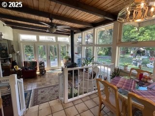 53742 Rosa Rd, Bandon, OR 97411 - sunroom / solarium with wooden ceiling with exposed beams, a wood stove, french doors, tile patterned floors, and a chandelier