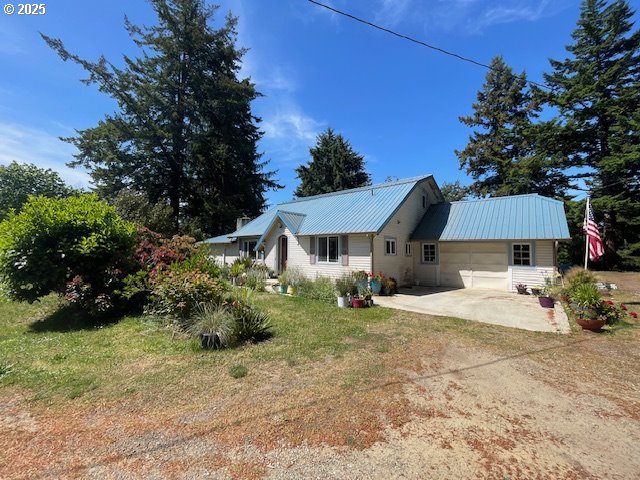 53742 Rosa Rd, Bandon, OR 97411 - view of front of home featuring concrete driveway, metal roof, a garage, and a front yard