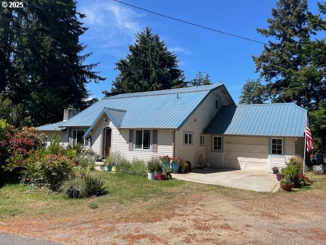 53742 Rosa Rd, Bandon, OR 97411 - back of house featuring concrete driveway, metal roof, and an attached garage