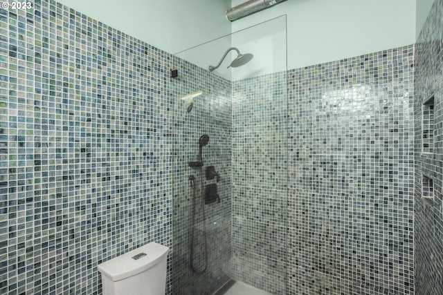 bathroom with a tile shower and toilet