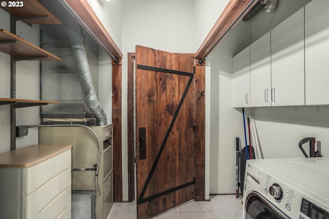 clothes washing area featuring cabinets, washer / dryer, and light tile patterned floors