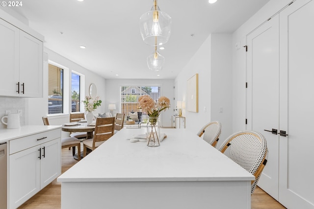 kitchen featuring decorative light fixtures, a kitchen island, dishwasher, and white cabinetry