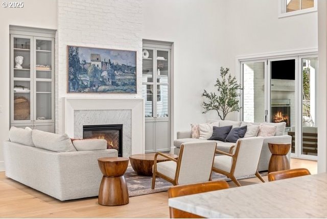 living area featuring a high end fireplace, light wood-style floors, and a high ceiling