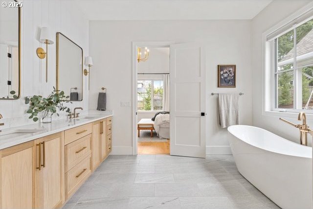 full bathroom featuring healthy amount of natural light, double vanity, and a soaking tub