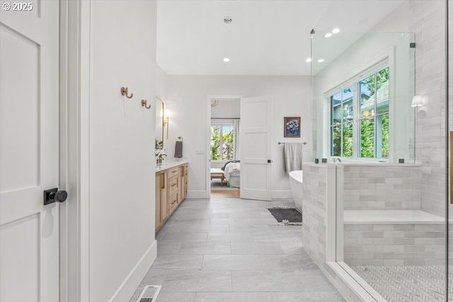 bathroom featuring vanity, a soaking tub, recessed lighting, baseboards, and a tile shower