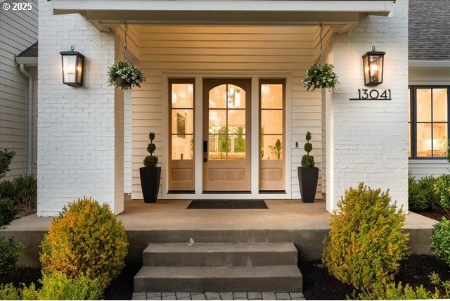 entrance to property featuring a porch and brick siding