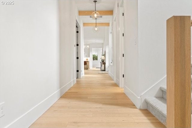 corridor featuring light wood finished floors, stairs, and baseboards
