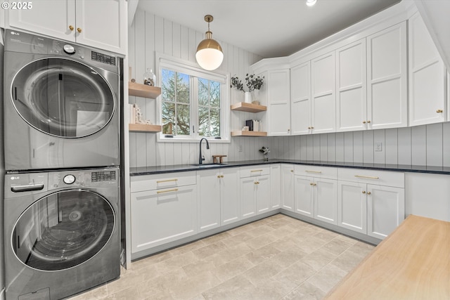 clothes washing area featuring stacked washer / drying machine and cabinet space