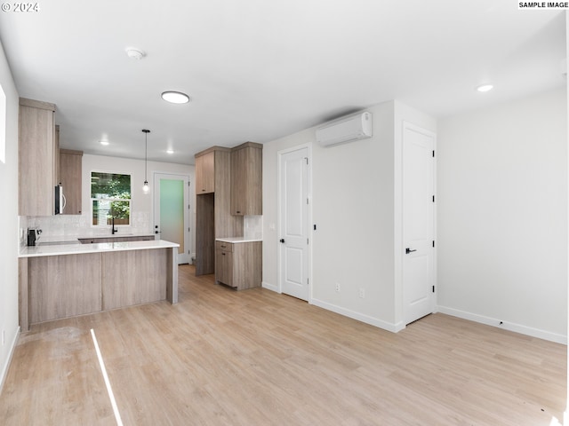 66 NE Stanton St, Portland, OR 97212 - kitchen with tasteful backsplash, a wall mounted AC, kitchen peninsula, hanging light fixtures, and light wood-type flooring