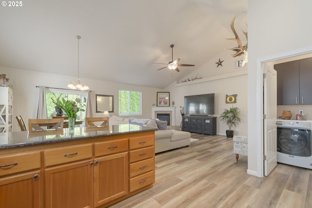 1281 Alderdale Dr, Junction City, OR 97448 - kitchen with washer / clothes dryer, ceiling fan, light wood-style floors, dark stone counters, and a chandelier