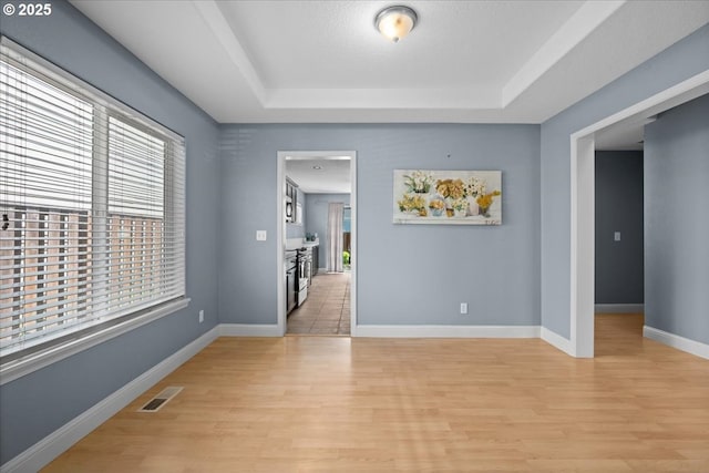 5836 NE Farnham St, Hillsboro, OR 97124 - spare room featuring light wood-type flooring, a tray ceiling, and baseboards