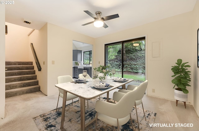 carpeted dining area with ceiling fan