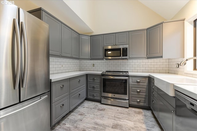 kitchen featuring gray cabinetry, lofted ceiling, and appliances with stainless steel finishes