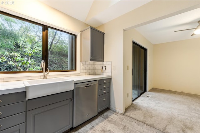 kitchen with lofted ceiling, sink, gray cabinets, backsplash, and stainless steel dishwasher