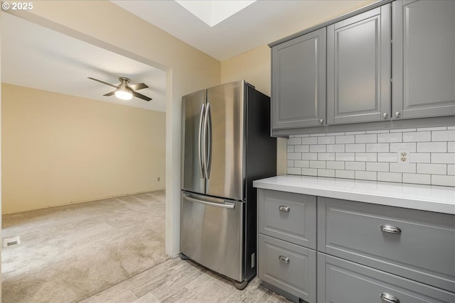 kitchen featuring gray cabinets, ceiling fan, stainless steel fridge, and backsplash