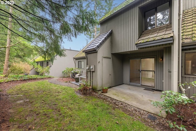 rear view of property featuring a lawn and a patio area