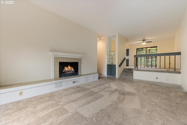 unfurnished living room featuring ceiling fan, a fireplace, and carpet