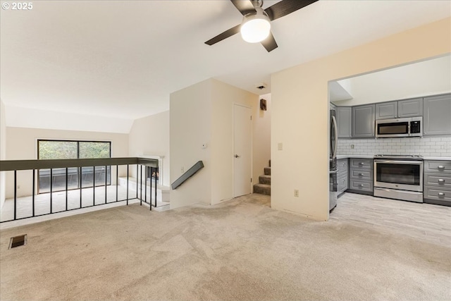 unfurnished living room featuring lofted ceiling, light carpet, and ceiling fan