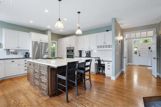 kitchen featuring white cabinets, stainless steel appliances, a breakfast bar, and tasteful backsplash