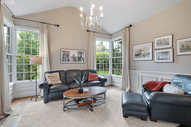living area with a chandelier, a wainscoted wall, a wealth of natural light, wood finished floors, and lofted ceiling