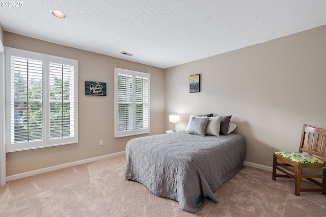 carpeted bedroom with baseboards, a textured ceiling, and visible vents