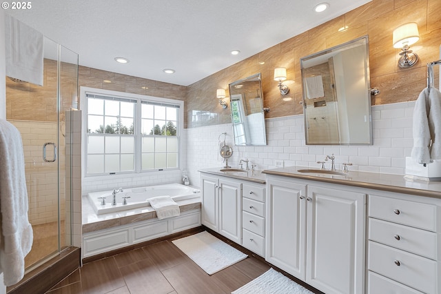 full bathroom featuring double vanity, a sink, a stall shower, and tile walls