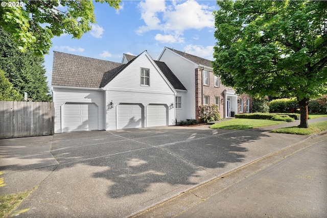 view of front of house featuring an attached garage, fence, and driveway