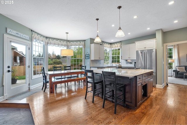 kitchen with freestanding refrigerator, a kitchen island, dark wood-type flooring, light countertops, and white cabinetry