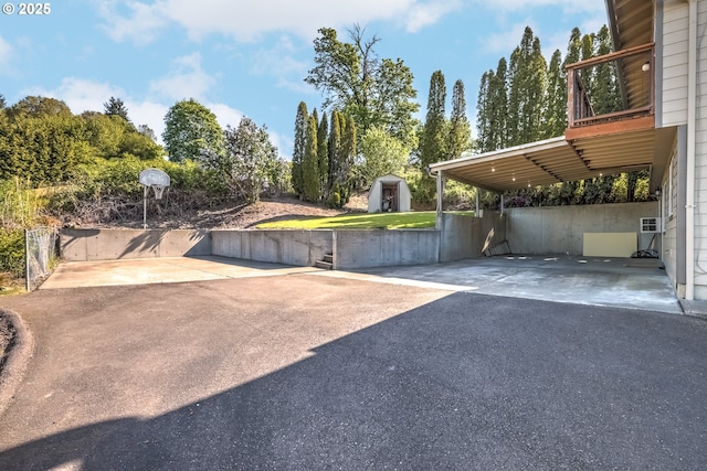 view of vehicle parking featuring a storage shed and driveway