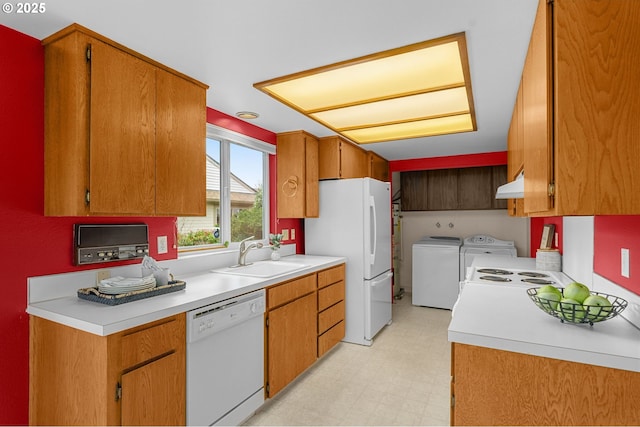 kitchen featuring white appliances, separate washer and dryer, under cabinet range hood, light countertops, and a sink