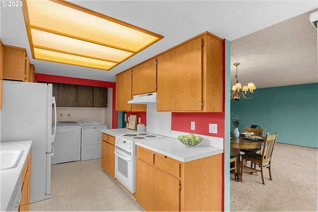 kitchen featuring an inviting chandelier, light countertops, white appliances, under cabinet range hood, and washer and clothes dryer