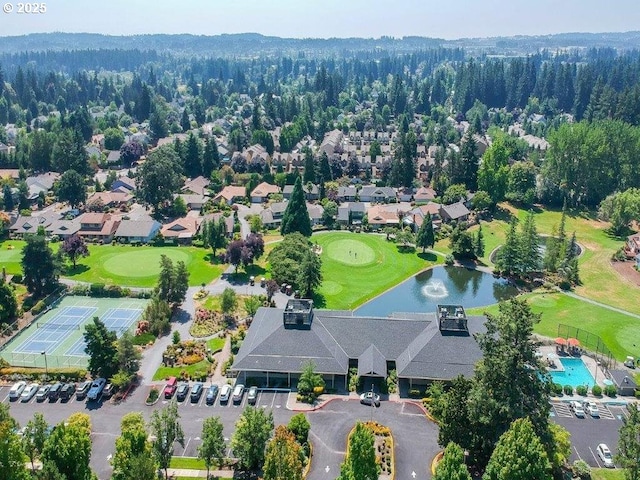 bird's eye view with view of golf course, a view of trees, and a water view