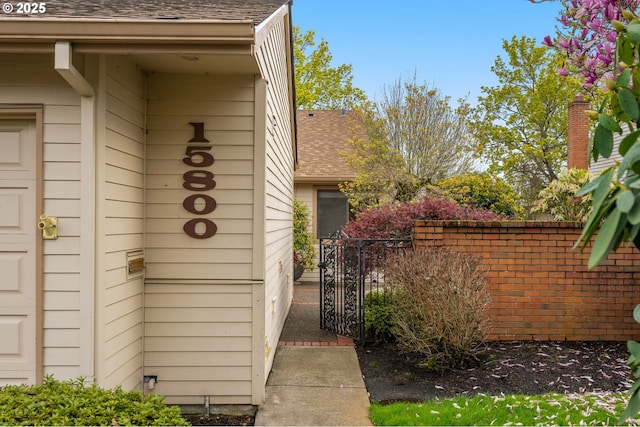 property entrance with roof with shingles and fence